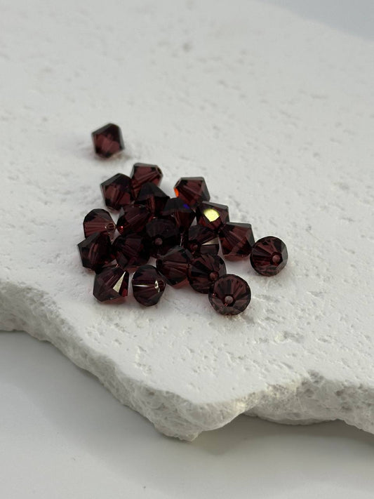 Burgundy bicone beads on white surface