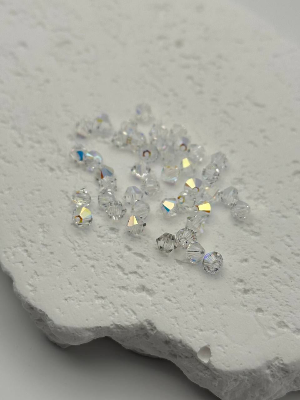 Clear crystal bicone beads on a textured white surface