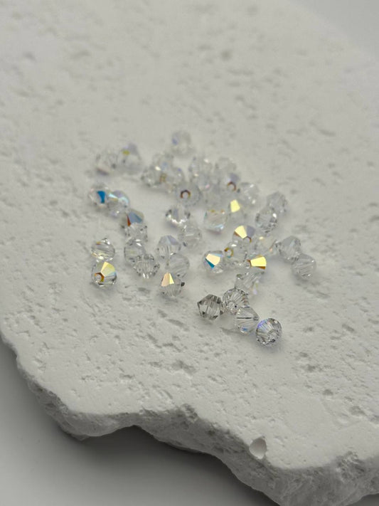 Clear crystal bicone beads on a textured white surface