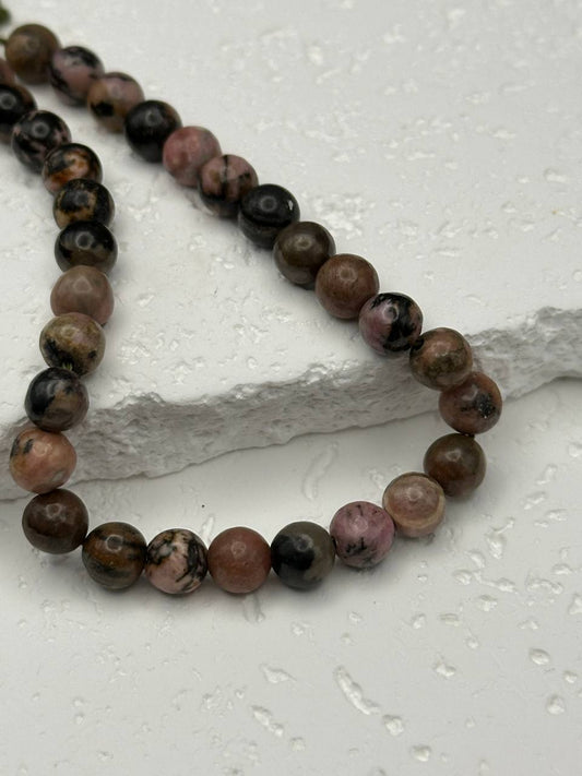 Rhodonite beads on white surface