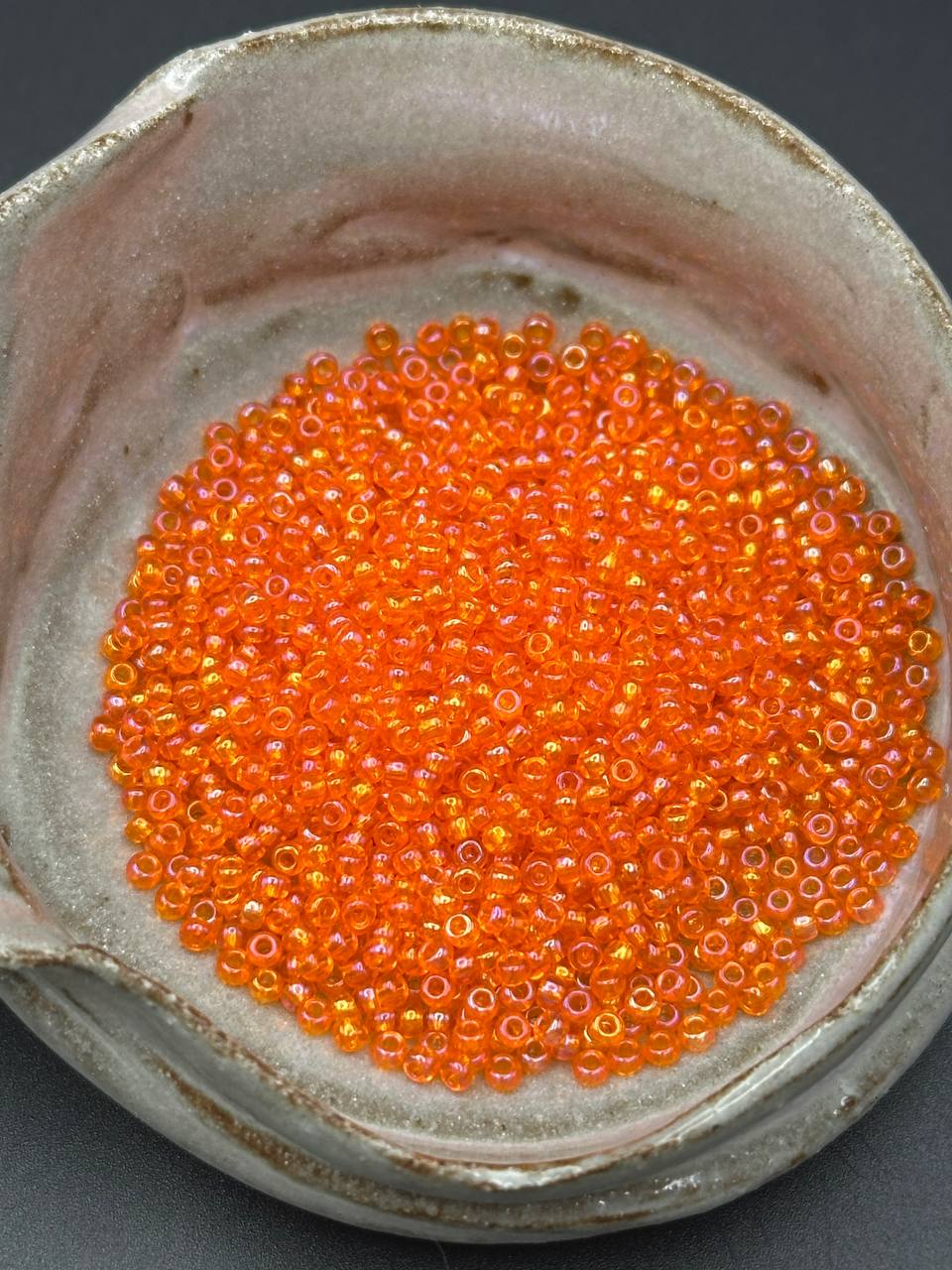 small container filled with rainbow orange beads