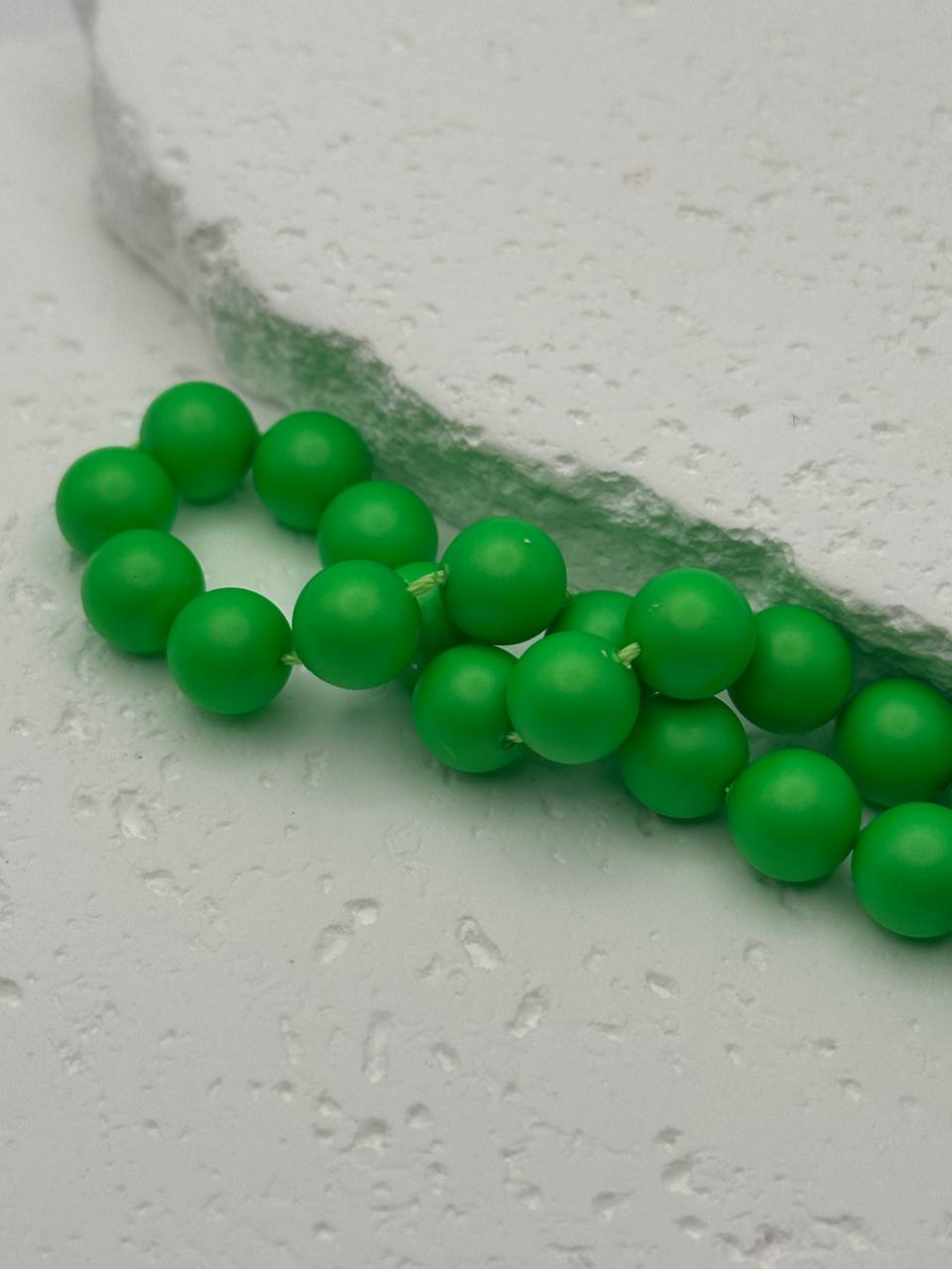 Green beads on a textured white surface