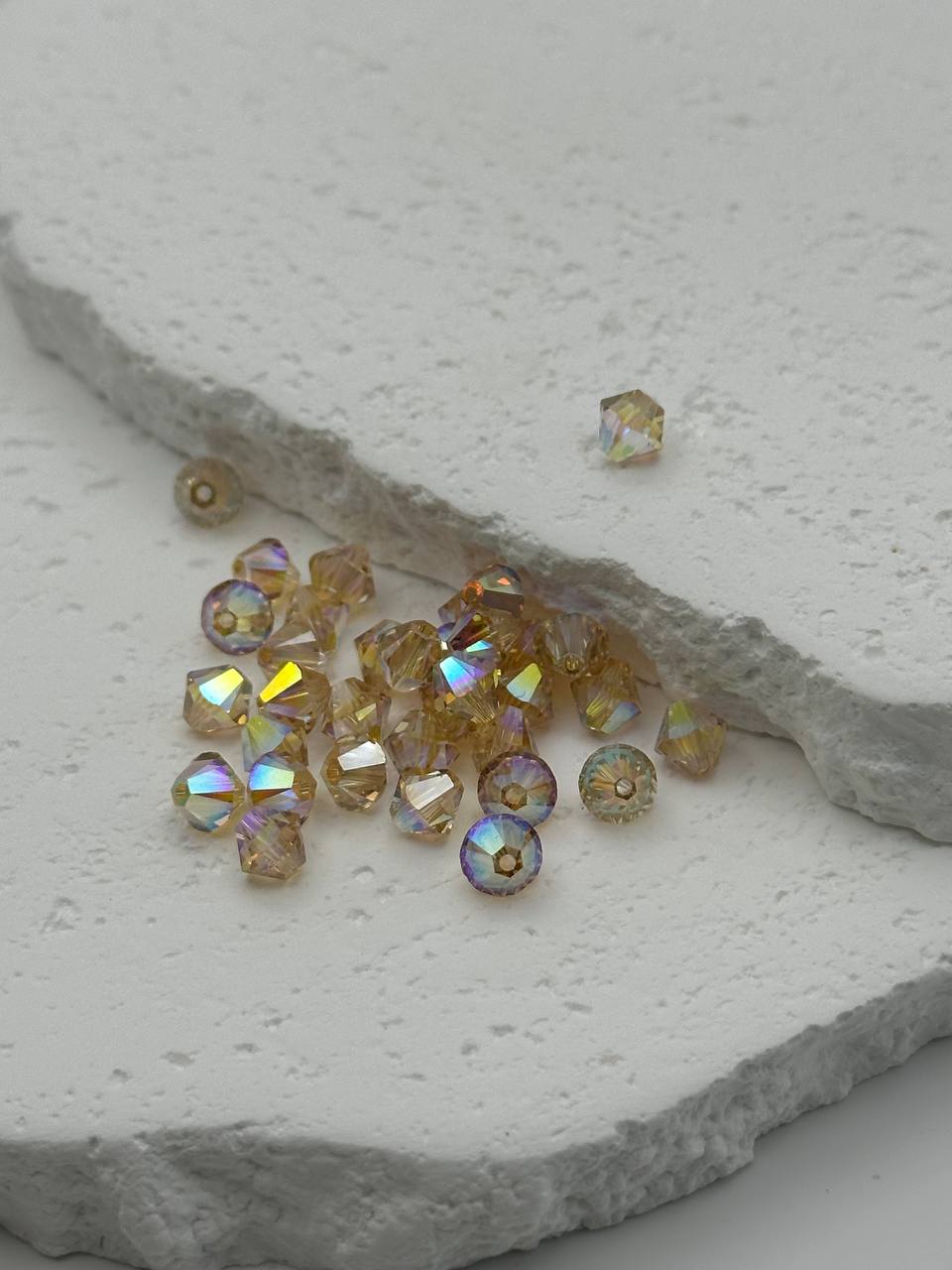 Small amber-colored bicone beads on a textured stone surface