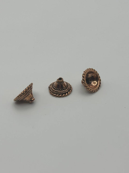 Three bronze-colored metal caps on a light gray background