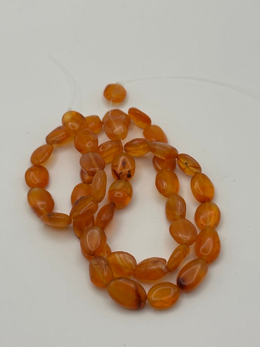 irregular nugget carnelian agate beads on white surface