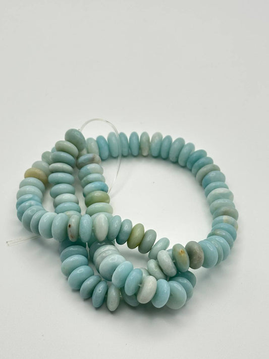 A string of light blue calcite rondelle beads on a white surface