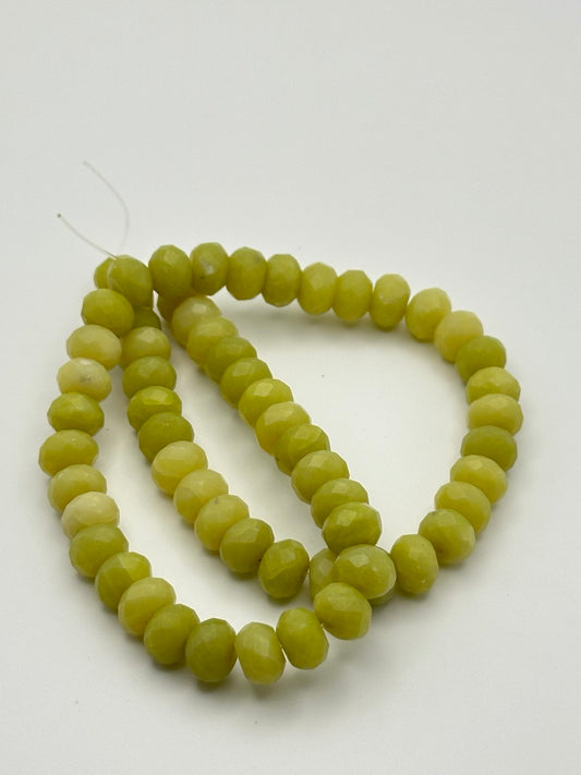 A string of olive green serpentine rondelle beads on a white surface
