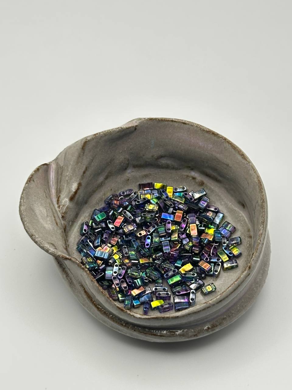 Ceramic bowl filled with colorful beads on a white background
