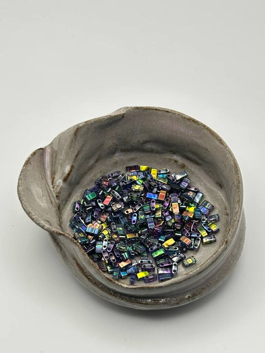 Ceramic bowl filled with colorful beads on a white background