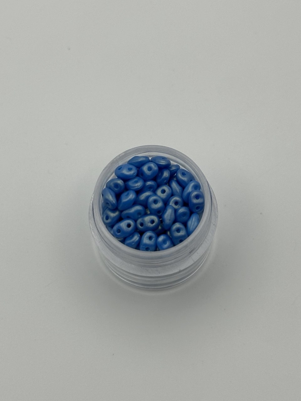 Small container filled with blue beads on a white background