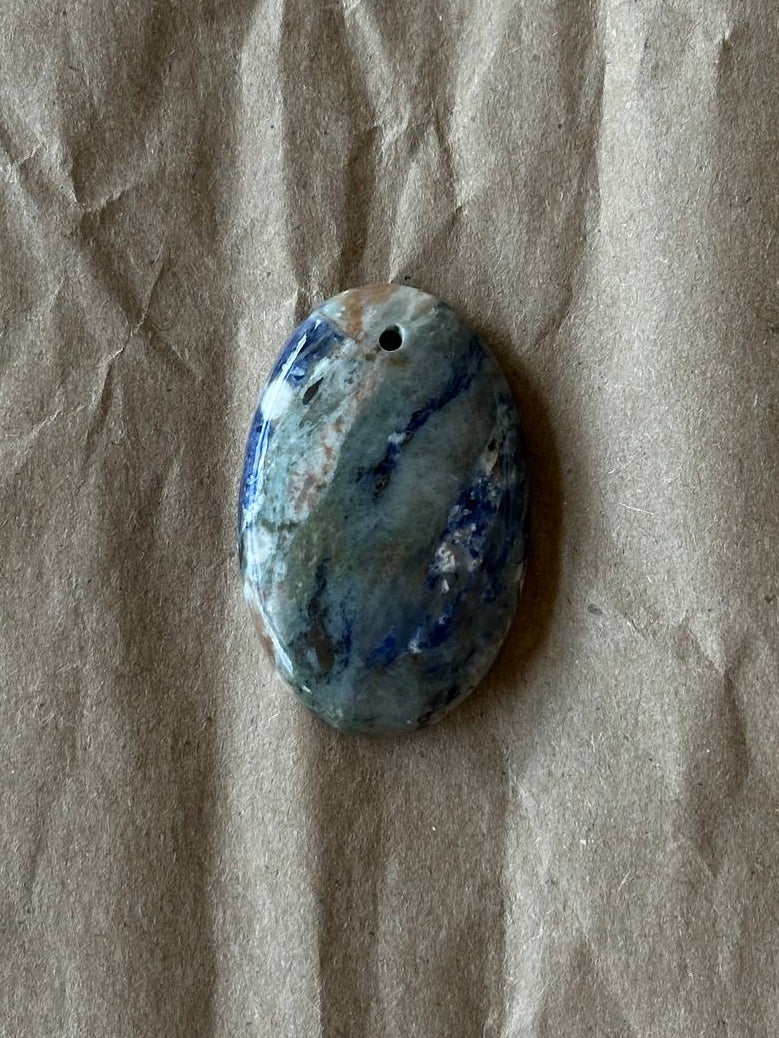 A smooth sodalite oval cabochon on brown paper background