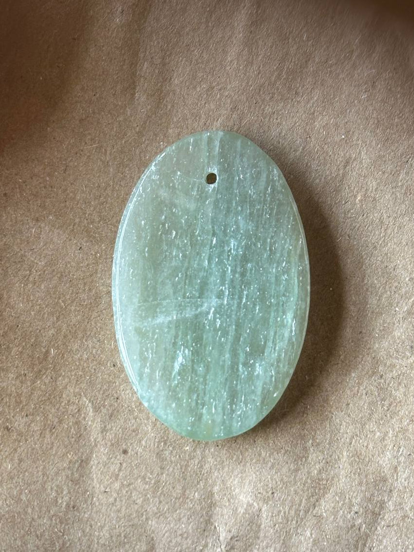 An oval aquamarine cabochon on brown paper background