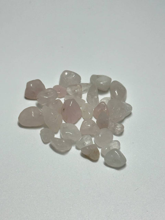 A small pile of rose quartz irregular chip beads on white background