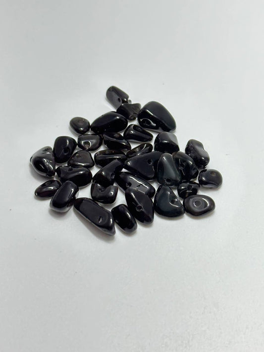 A pile of polished black tumbled agate stones, arranged on a plain white surface.