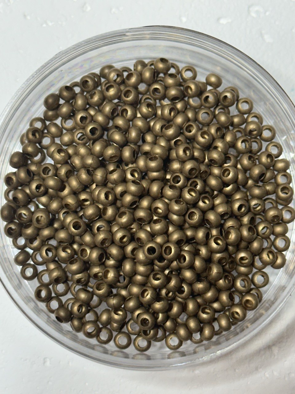 A small pile of genuine metal brass round size 6 seed beads