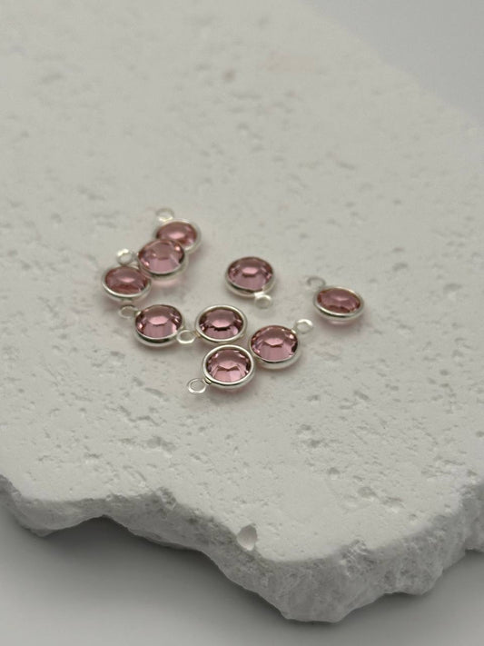 Silver jewelry with amethyst chatons on a textured white surface