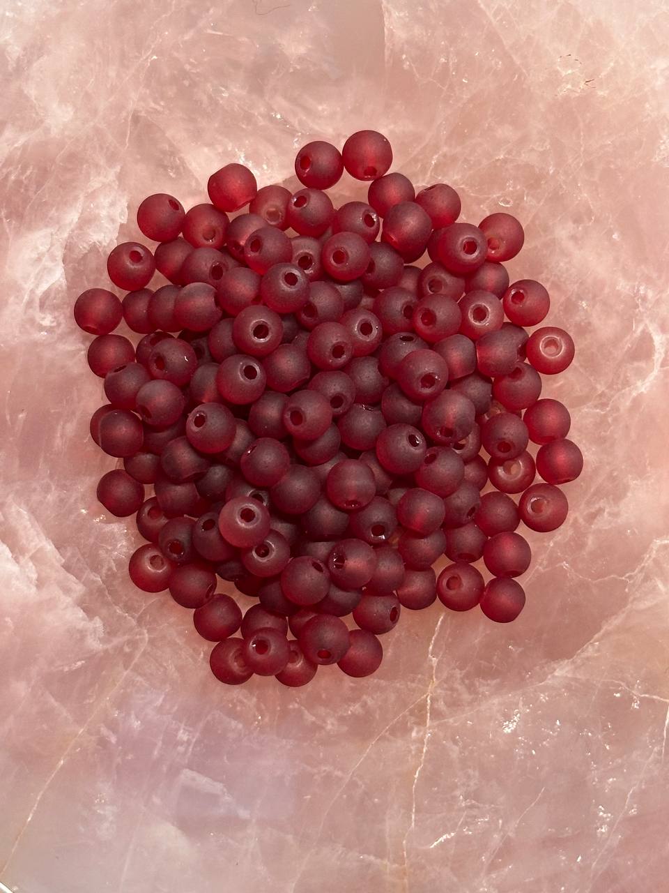 Cluster of burgundy beads on a textured pink surface