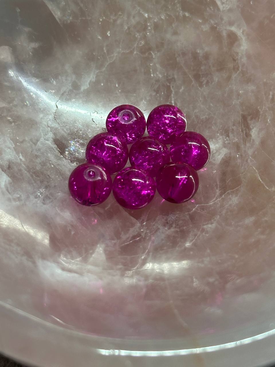 Pink crackle beads on a textured white surface