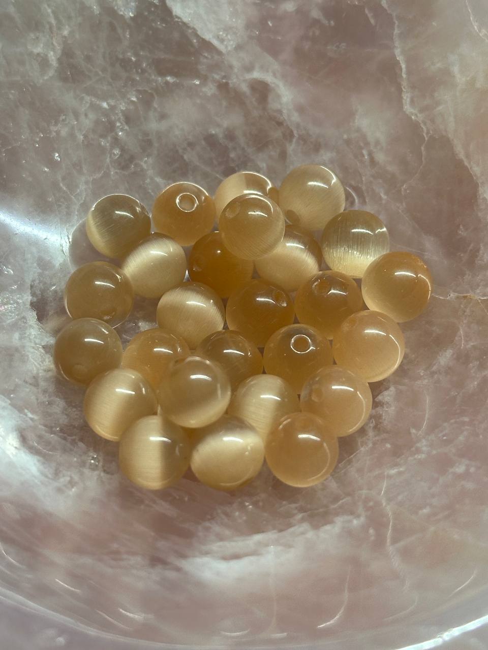 Cat eye peach glass beads on a marble surface