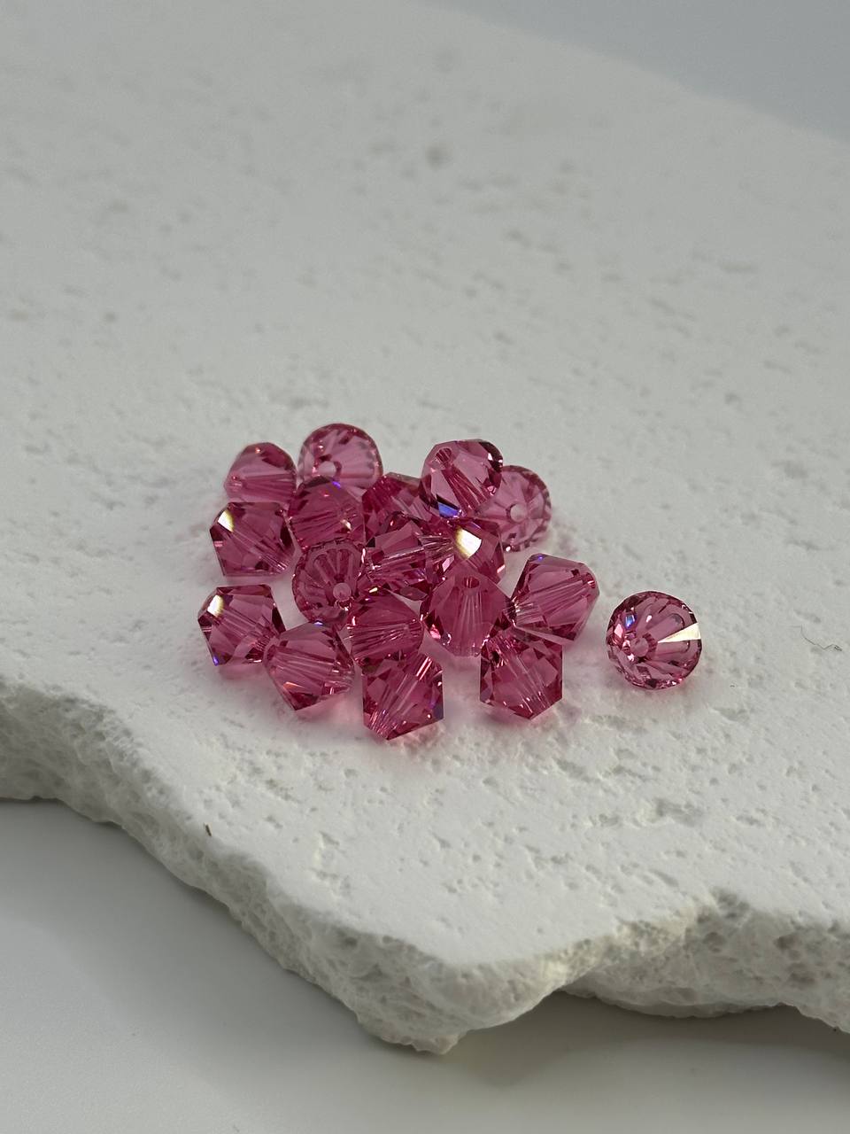 Pink bicone beads on a textured white surface