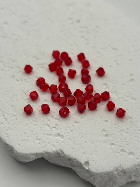 Red bicone beads on a textured white surface