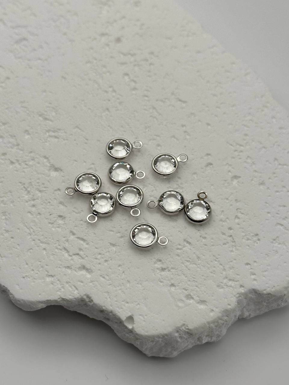 Silver jewelry components on a textured stone surface