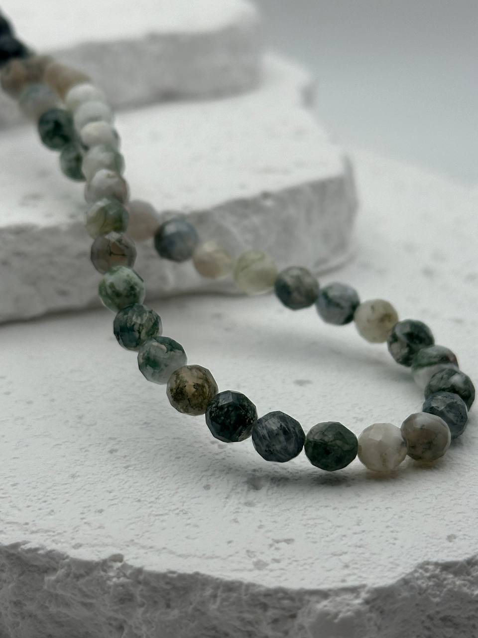 Necklace with green and gray beads on a textured surface
