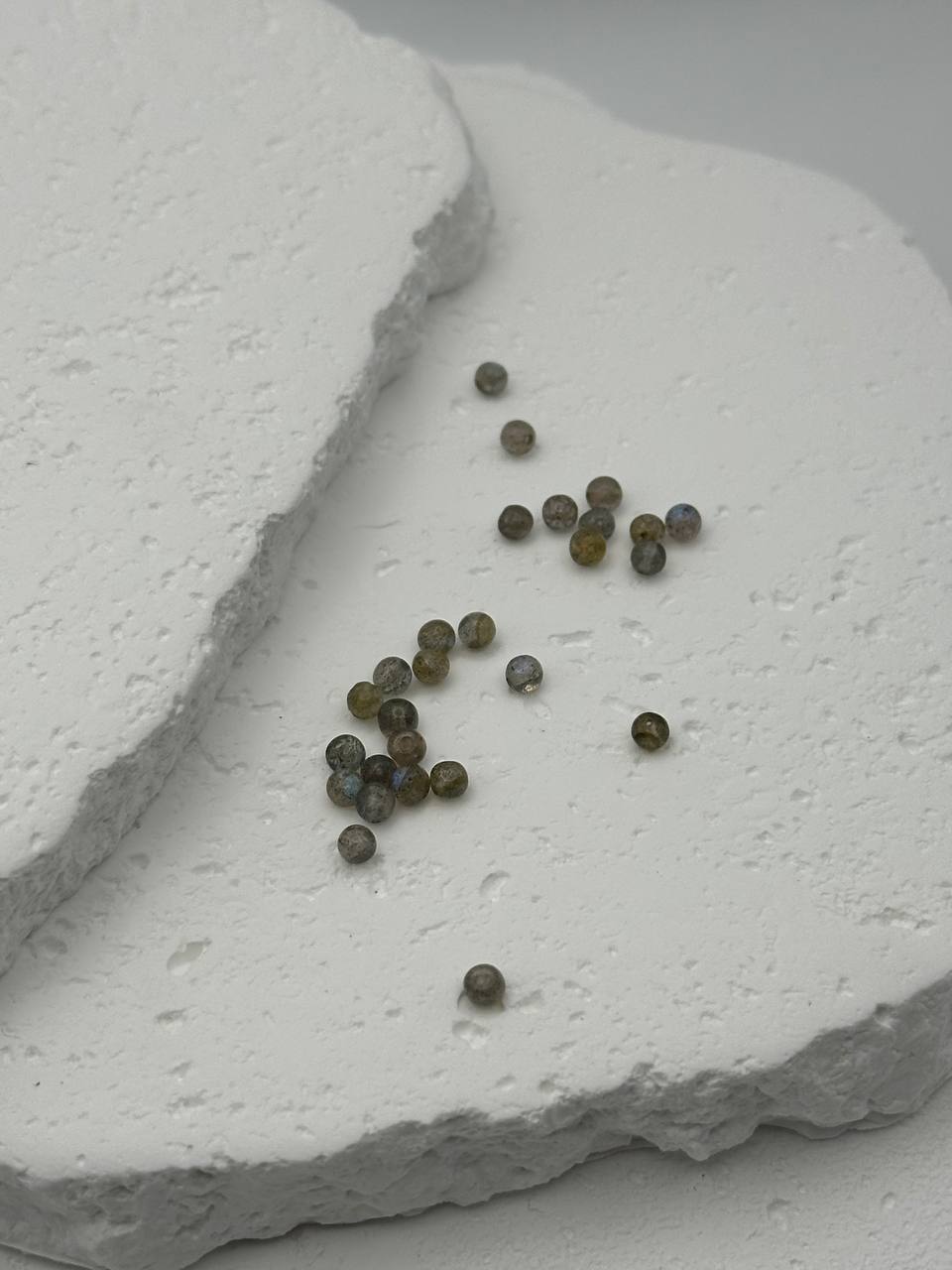 Small labradorite beads on a textured white surface