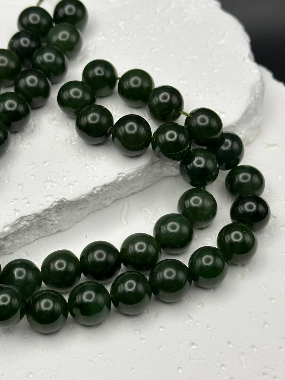 String of dark green beads on a light gray surface