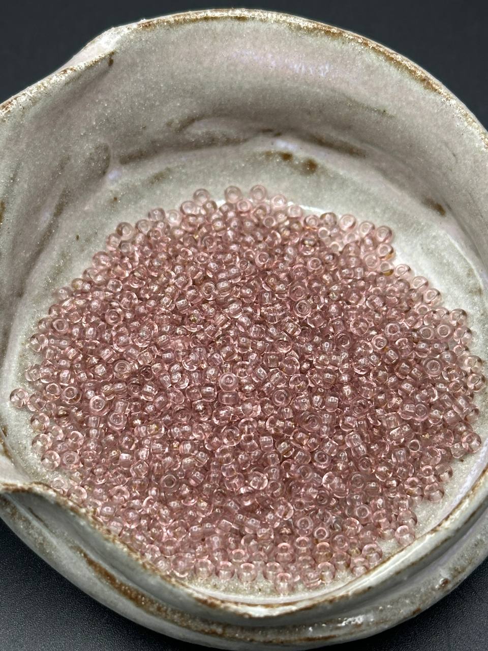Small container filled with brown beads on a dark background