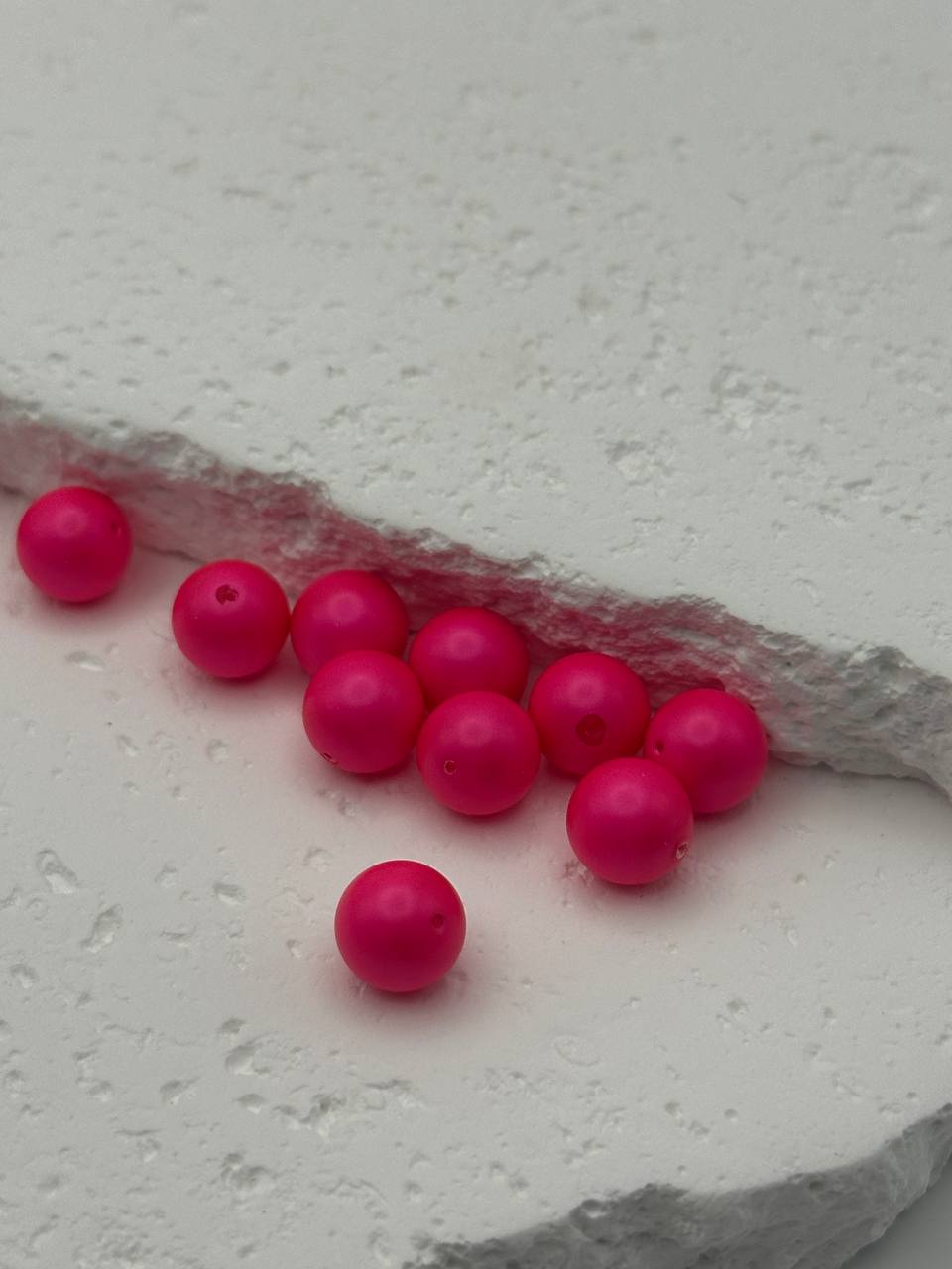 Pink neon beads on a textured white surface