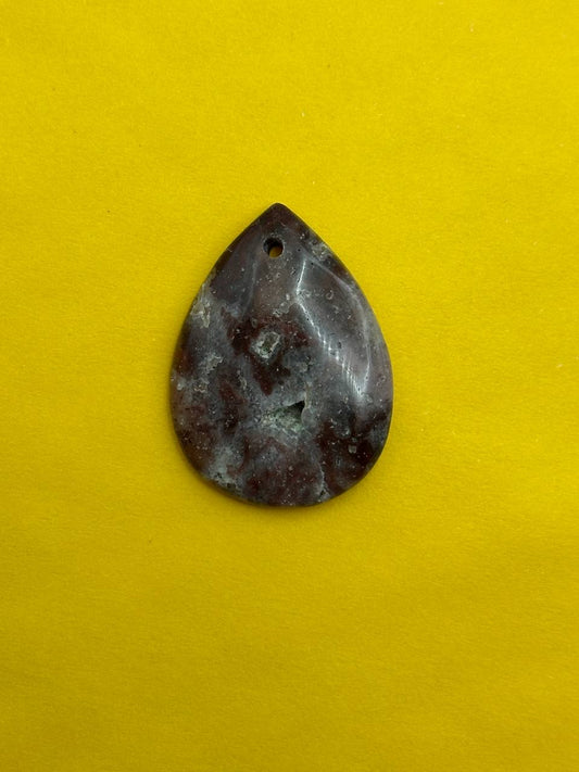 Teardrop-shaped stone pendant on a yellow background