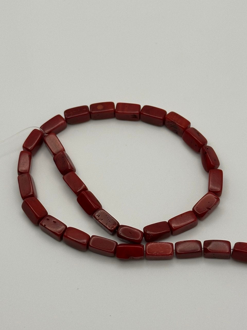 red coral rectangular beads on white surface