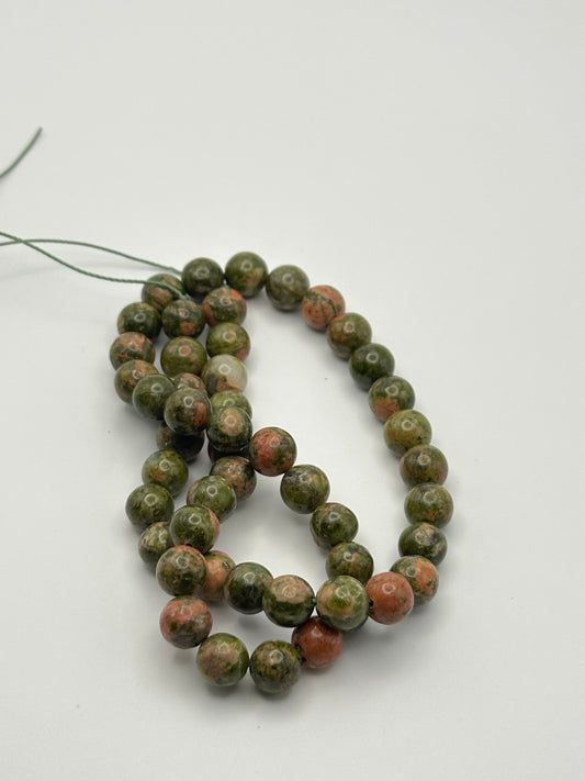 String of green and brown unakite beads on a white background
