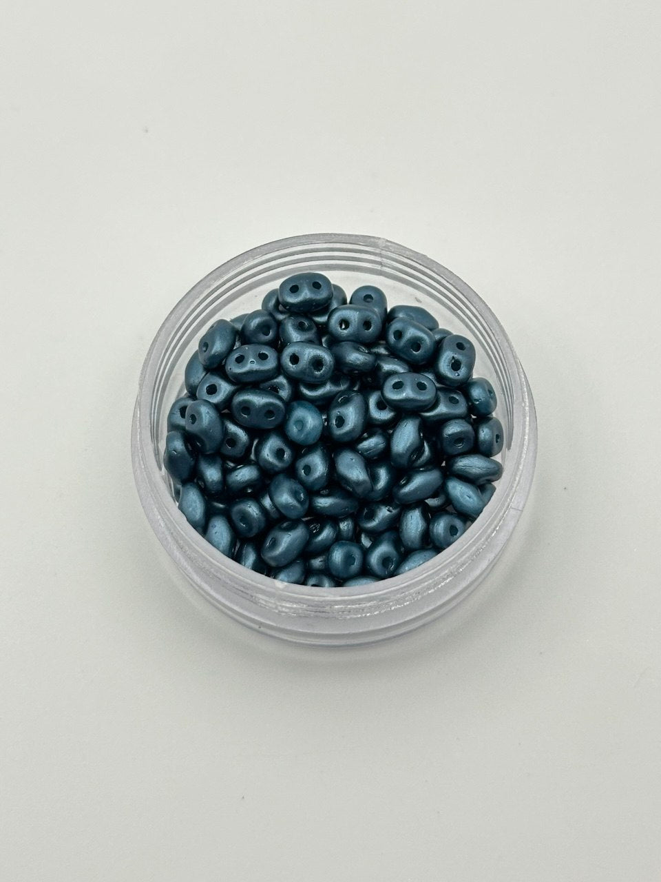 Clear container filled with blue beads on a white background