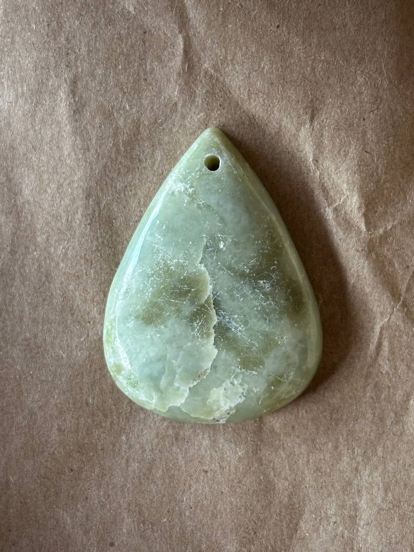 Serpentine teardrop cabochon on brown paper background