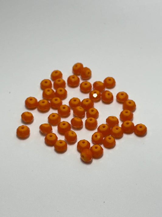 A pile of small, round, orange translucent beads with a central hole, arranged on a plain white surface.