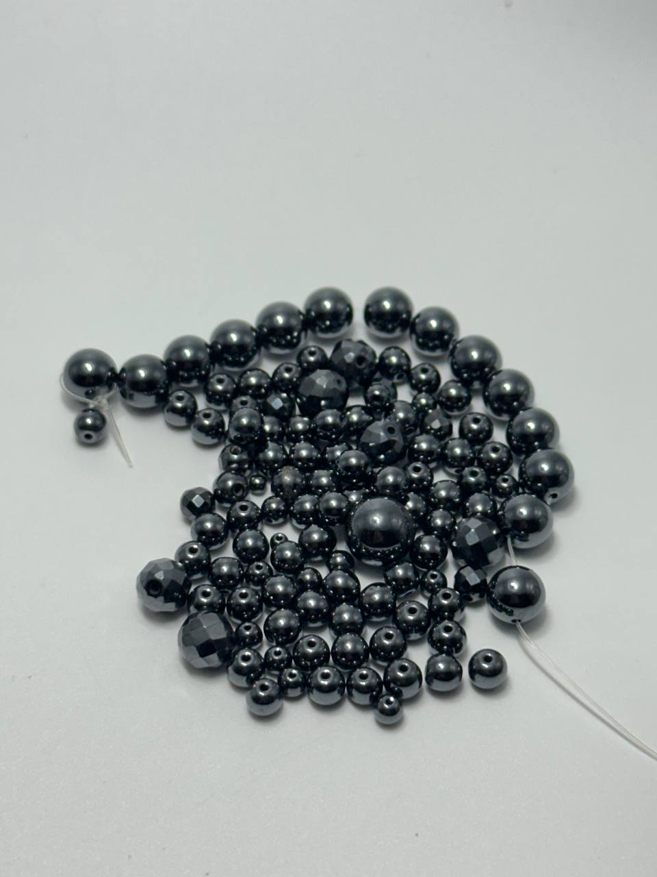 A small pile of black hematite round beads on white surface