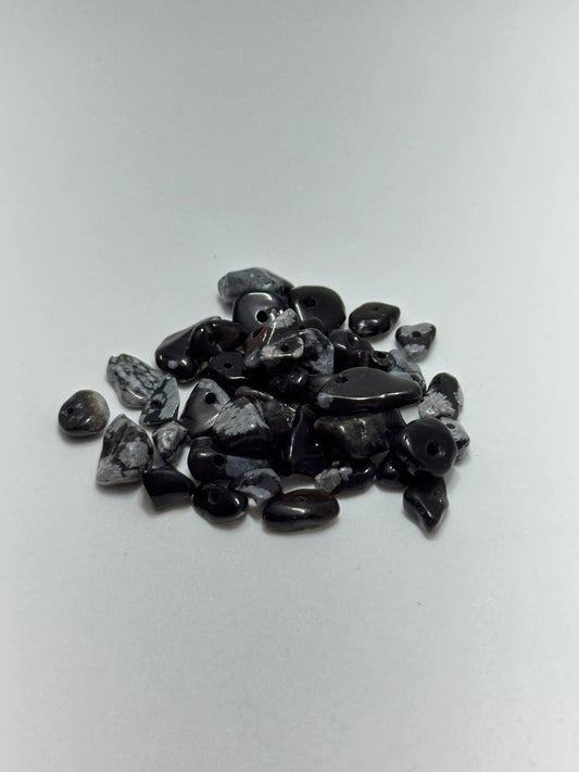 A small pile of polished black and gray stone chips or tumbled stones on a plain light background.