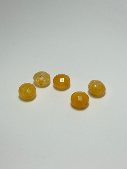 Five small faceted amber-yellow beads arranged on a plain light background.