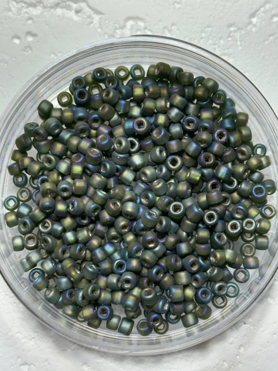 A small pile of size 6 matsuno rocaille iris seed beads on white surface