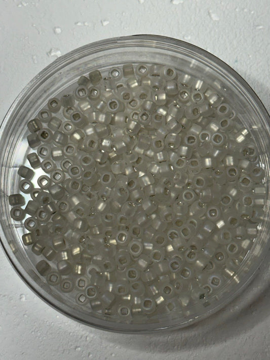 A small pile of matsuno round beads in white crystal matte AB with square holes on white surface