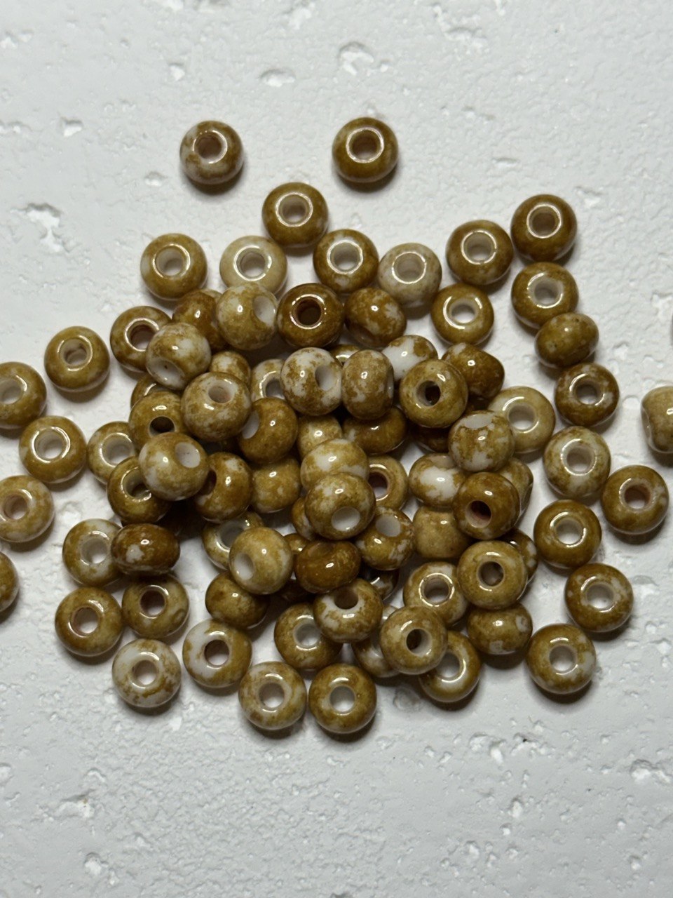 a small pile of czech size 2 speckled oats beads on white surface
