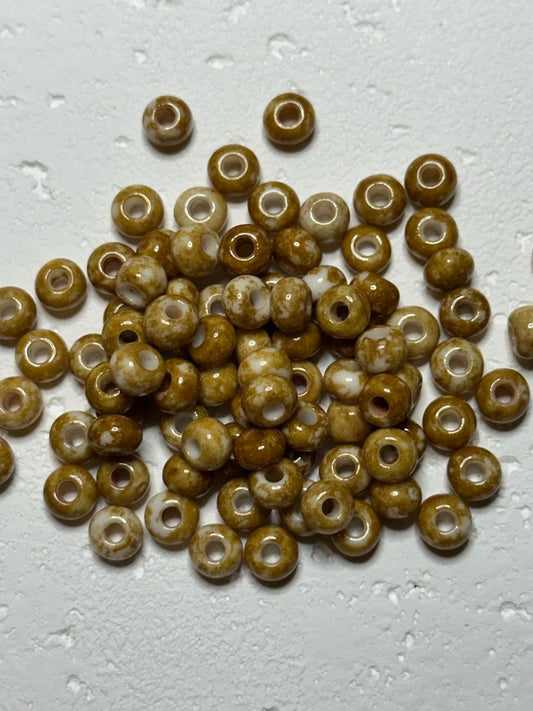 a small pile of czech size 2 speckled oats beads on white surface