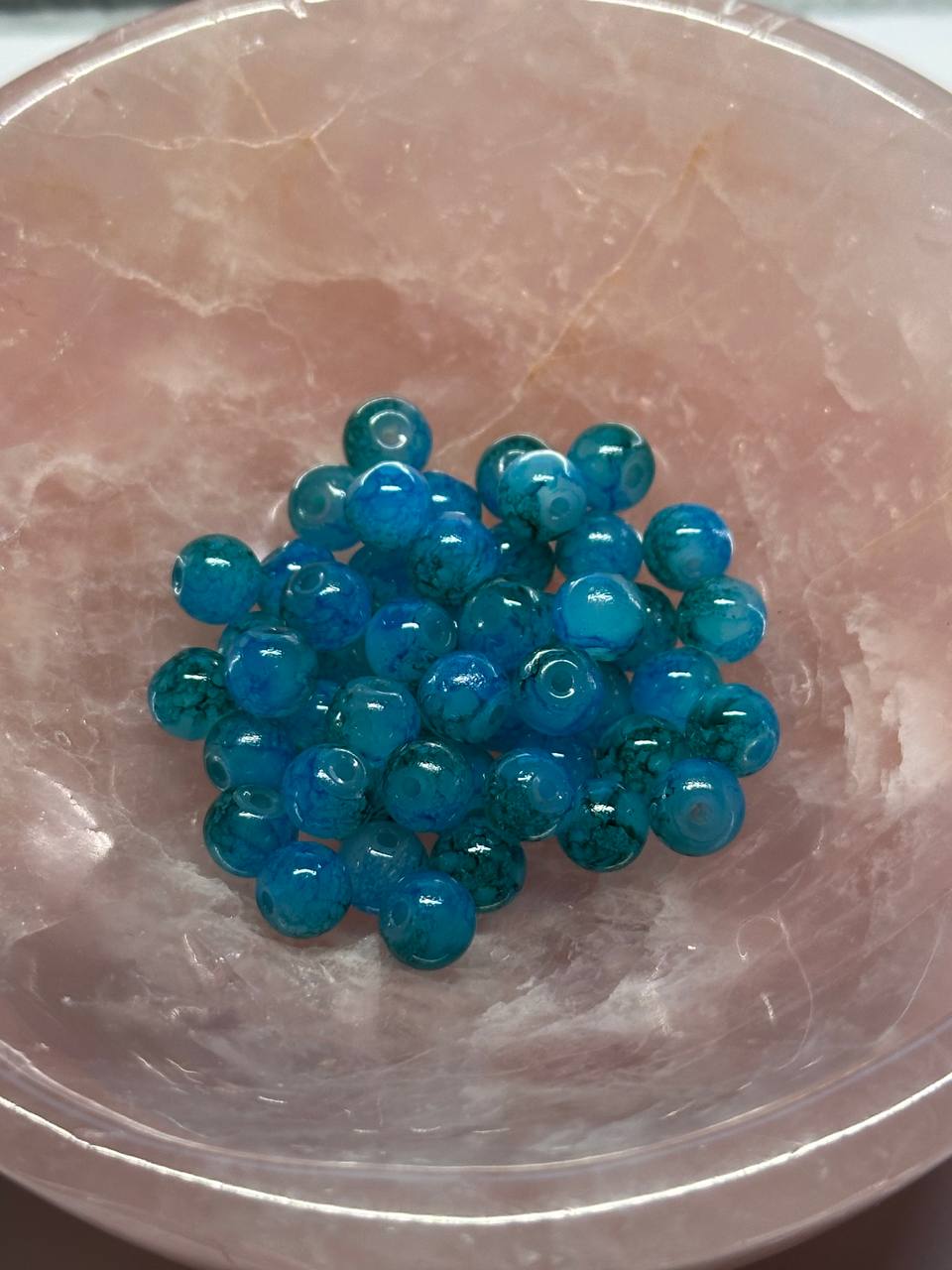 Blue beads on a pink stone surface