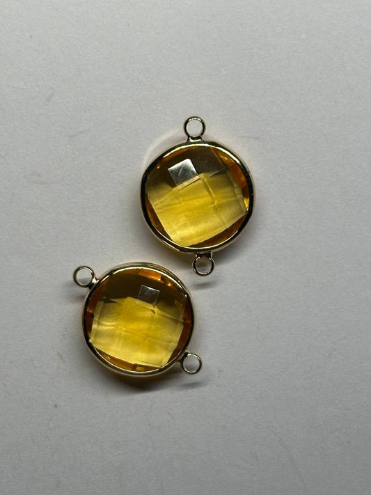 Two yellow stone pendants with gold settings on a gray background