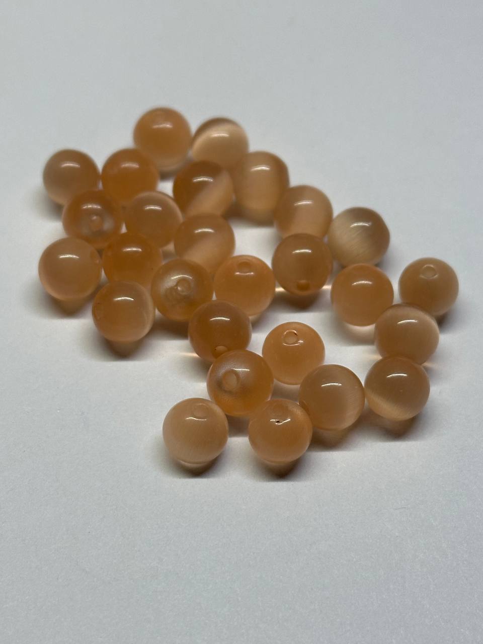 Peach cat eye beads on a light gray background