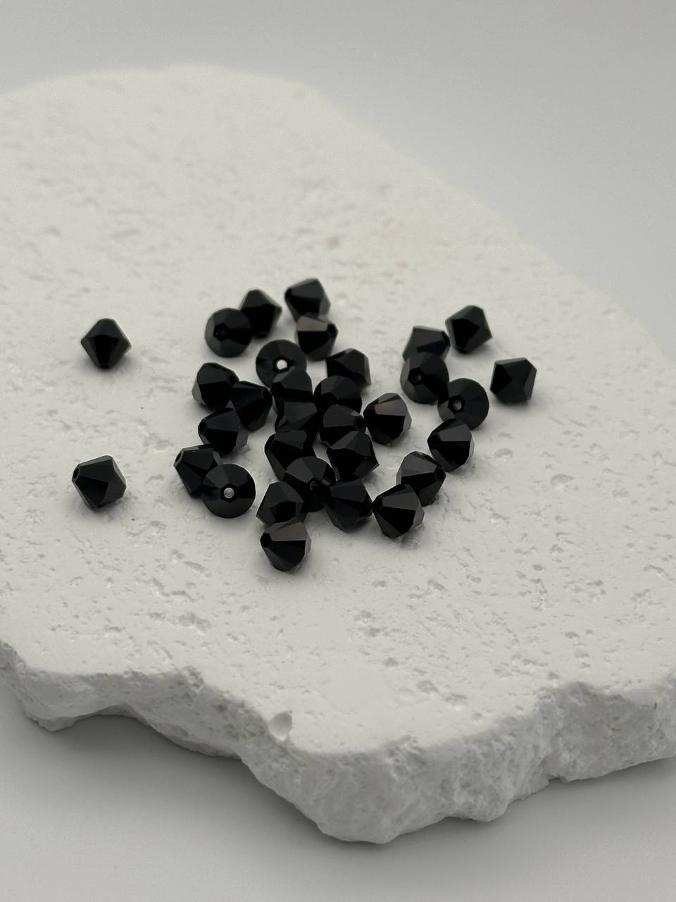 Black bicone beads on a textured white surface