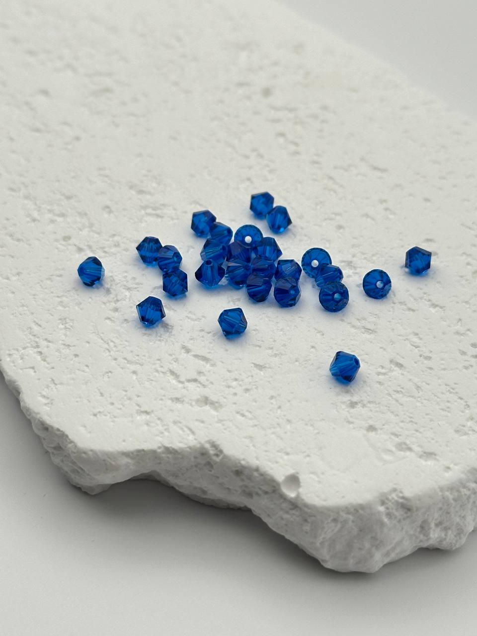 Blue beads scattered on a textured white surface