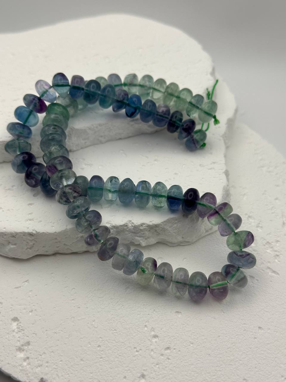 Strand of multicolored  beads on a white stone surface